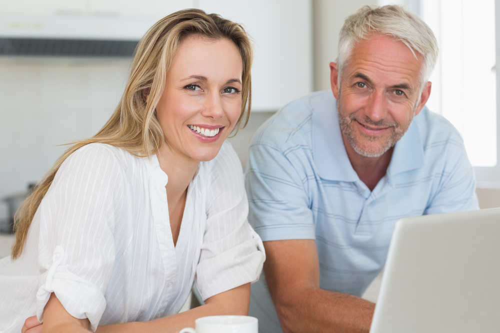smiling man and woman in front of laptop
