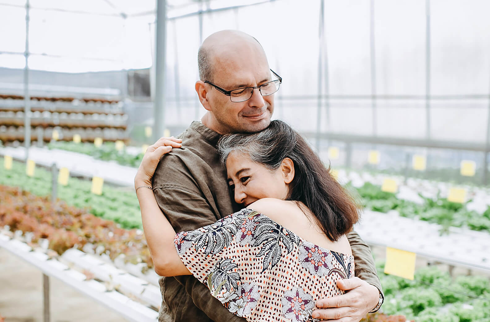 an older couple embracing in a greenhouse