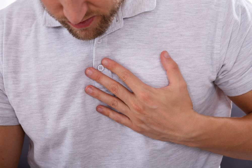 man touching his chest while suffering pain