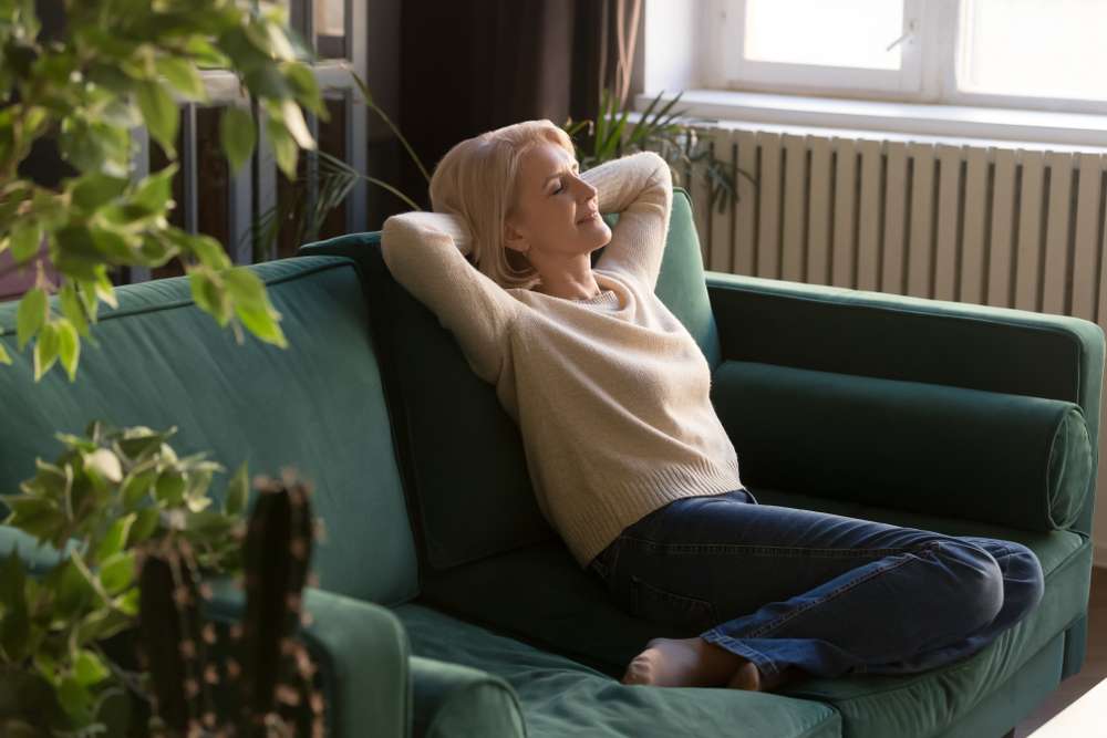 serene older woman in casual clothes relaxing on couch