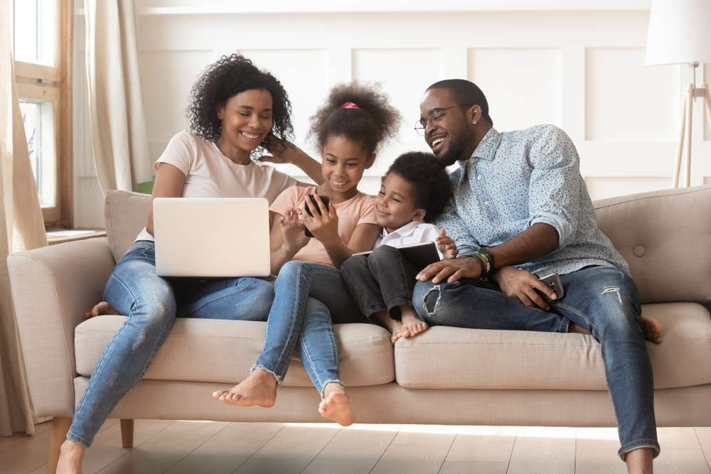 young family of four sitting on couch together