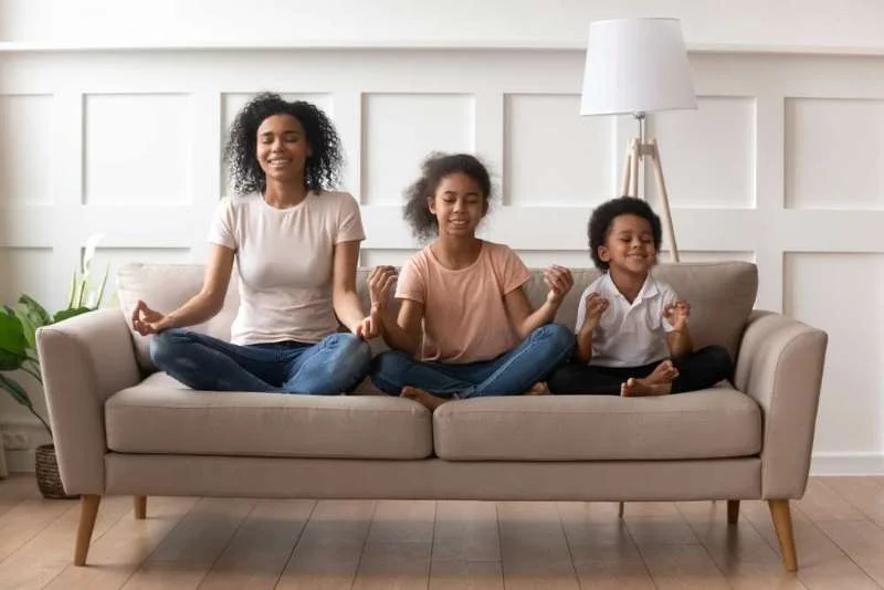 African American mother, daughter and son sitting on couch meditating