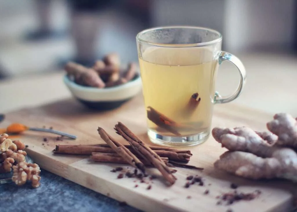 drink in glass mug, cinnamon sticks and ginger root